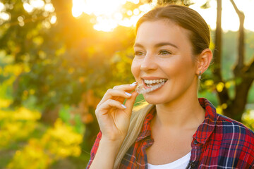 Invisalign orthodontics concept - Young attractive woman holding - using invisible braces or...