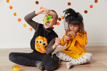 Fototapeta premium Cute little girl and boy in witch and spider costume play at home. Halloween party