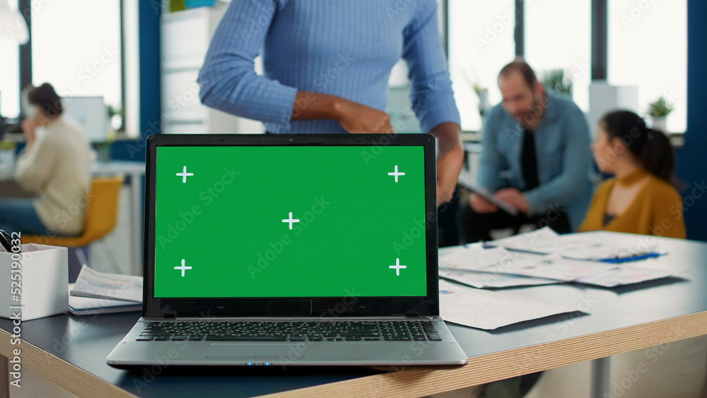 Poster laptop computer with green screen on desk in front of african american startup employee looking at p