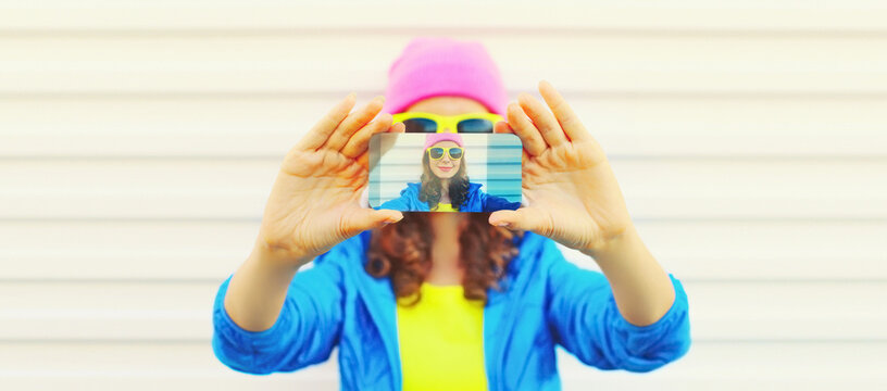 Close up of modern young woman stretching her hands taking selfie with smartphone on white background