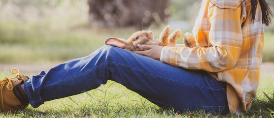 beautiful pretty portrait of young Asian woman person with cute rabbit in pet and animal care concept, happy female holding bunny at nature outdoor field with friendship, easter concept