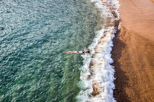top view of woman floating in the sea near sandy beach