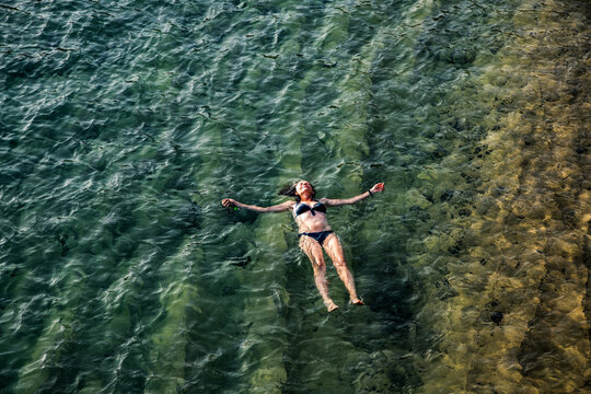 top view of woman floating in the sea near sandy beach