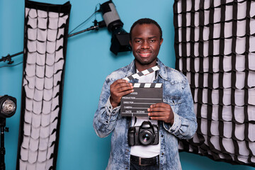 African american producer with clapperboard standing in studio having professional production...