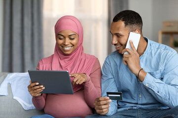 Pregnant Muslim Couple Making Online Payments With Digital Tablet And Credit Card