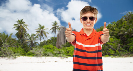 travel, tourism and summer vacation concept - portrait of happy smiling boy in sunglasses and red...