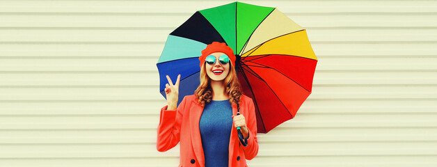 Autumn portrait of happy cheerful smiling young woman with colorful umbrella wearing red coat and beret on white background