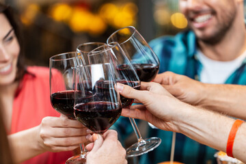 leisure, people and celebration concept - close up of happy friends drinking red wine and toasting...