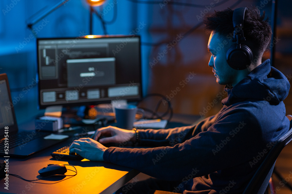 Poster cybercrime, hacking and technology concept - male hacker in dark room writing code or using computer
