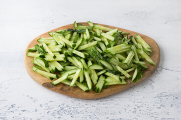 Wooden board with fresh cucumber sliced into julienne on a light blue background, top view. Cooking delicious homemade vegan food - 525195408