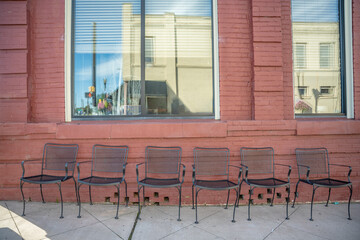 In a charming small town, Inman, S.C., cute iron chairs sitting out on the sidewalk in front of a restaurant with brick exterior, on famous Mill Street.