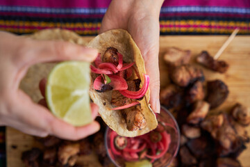 Woman hand pouring lemon to a fried pork belly taco