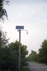 a pole with a solar battery, a street lamp with a solar battery, against the backdrop of nature and the sky