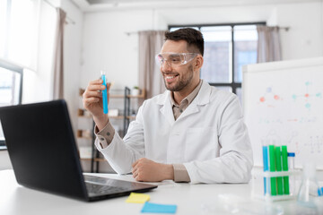 distance education, school and science concept - happy smiling male chemistry teacher with laptop computer and test tubes having online class at home office