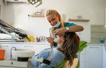 Female dentist examining a patient's teeth in the dentist office.
