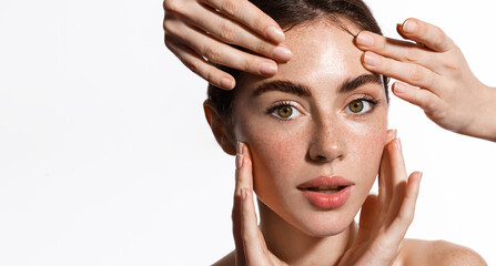 Hands massaging woman face. Girl looking at camera while receiving facial massage on clear, glowing skin, spa and cosmetology concept, white background