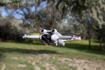 Close up drone with camera sensors and props flying in air with nature behind - DJI Mini 3 Pro...
