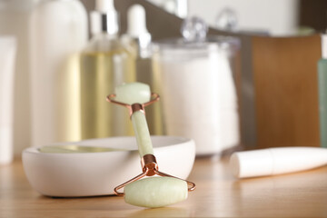 Natural face roller and cosmetic products on wooden table