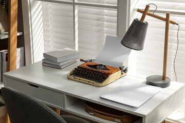 Comfortable writer's workplace with typewriter on desk in front of window