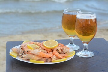 Cold beer in glasses and shrimps served with lemon on beach