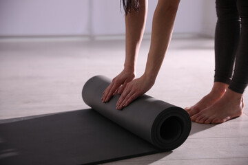 Woman rolling yoga mat in studio, closeup