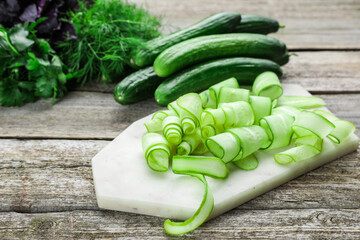 Fresh ripe cucumbers and greens on wooden table