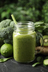 Delicious green juice and fresh ingredients on black table