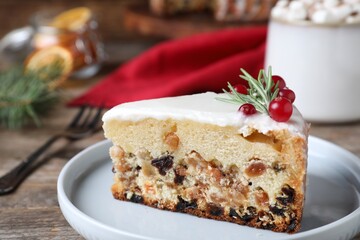 Slice of traditional Christmas cake decorated with rosemary and cranberries on table, closeup