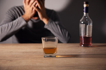 Bottle and glass of whisky and sad man