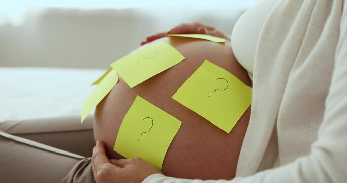 Yellow sticky notes with questions marks attached on big belly of unrecognizable pregnant woman resting sit on bed at home, expectant mother choosing name for unborn baby, guess gender of baby concept