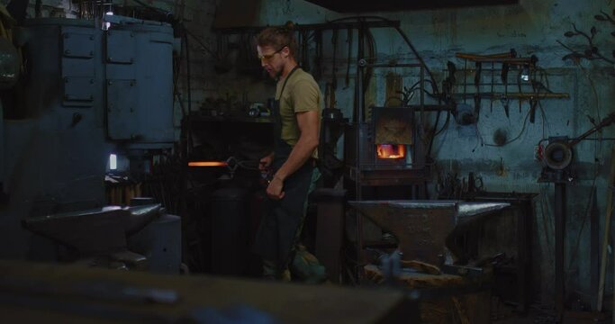 modern forge workshop, blacksmith put workpiece in automatic forging hammer, 4K, Prores