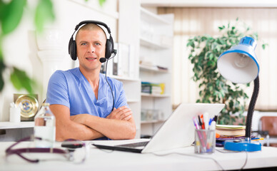 Hotline service. Doctor consulting patient online via laptop indoors. Telemedicine concept