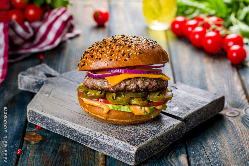 Wall mural burger with meat patty and jalapeno, vegetables and red onion on the board