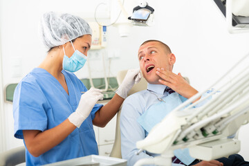 Fototapeta premium Male patient shows sick tooth to a dentist in a dental clinic