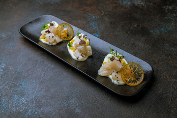 Sashimi scallop on a plate with sauce and mando and orange chips