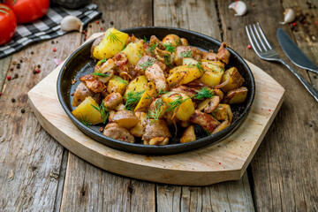 pan-fried chicken with potatoes and mushrooms on old wooden table