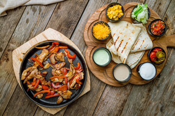 fajitas with chicken and bell pepper on the board with sauces top view