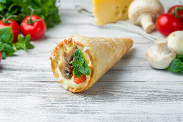 pizza in a cone with mushrooms, tomatoes, cheese and basil on white wooden table