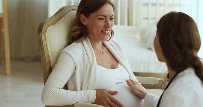 Obstetrician-gynecologist touch belly of pregnant woman express care, close up. Expectant mother talk to doula, get psychological support before childbearing at home visit. Prenatal medicare concept