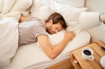 Sleeping, resting and sleepy man lying in bed with his eyes closed in a deep sleep in his bedroom....