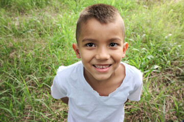 poor child smiling on grass field looking at camera