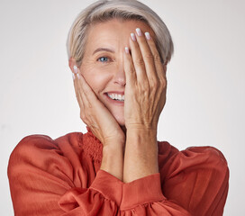 Eye, half and smile of a senior woman isolated against a grey background in a studio. Portrait of an elderly model lady in beauty with hands over her face in wellness, health and teeth.