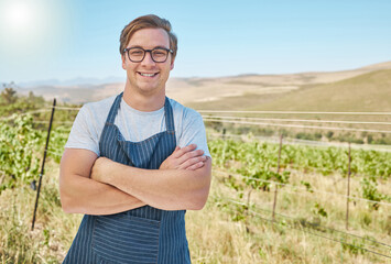 Vineyard and happy farmer man in the countryside with smile at a farm in nature in summer. Health, agriculture and success portrait of a young worker on a field in sustainability on a sunny day.