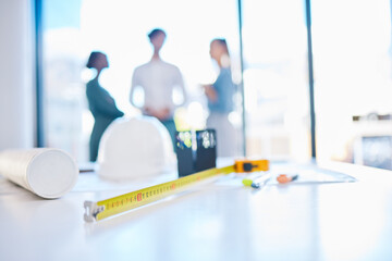 Fototapeta premium Creative engineering designer discuss building plans in a corporate business. Measure tape on a table or desk in an architecture company office with engineer employee consulting in the background