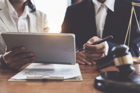 Business woman and lawyers discussing contract papers with brass scale on wooden desk in office. Law, legal services, advice, Justice concept