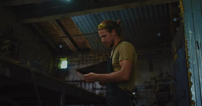skilled smith is making exclusive sharp steel knife in old traditional workshop, 4K, Prores