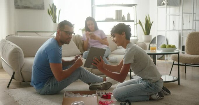 Excited boy shows father figure with constructor on tablet
