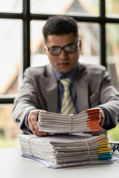 Businessman working piles of paper files to search for information on his desk at home ready. computer keyboard Work in piles of paperwork and unfinished paperwork 