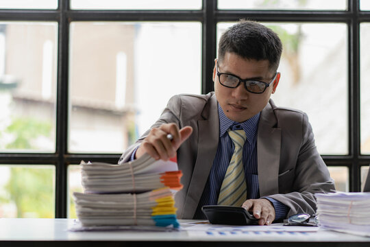 Businessman working piles of paper files to search for information on his desk at home ready. computer keyboard Work in piles of paperwork and unfinished paperwork 