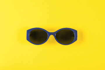 Stylish blue sunglasses on a yellow background.